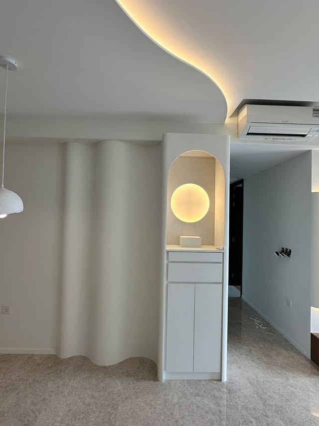 Organic curved partition wall with cove lighting and arched niche
