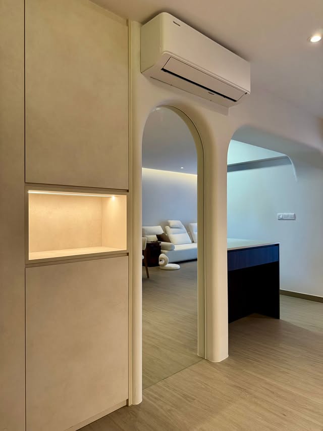 Arched opening into a living room with a recessed cove-lit cabinet